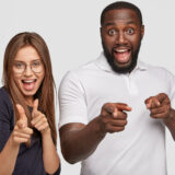 Mutliethnic teenagers have positive expressions, point at you with confident looks, look into distance, pose against white background. Hey, guy we follow you! Ethnicity, positive emotions concept